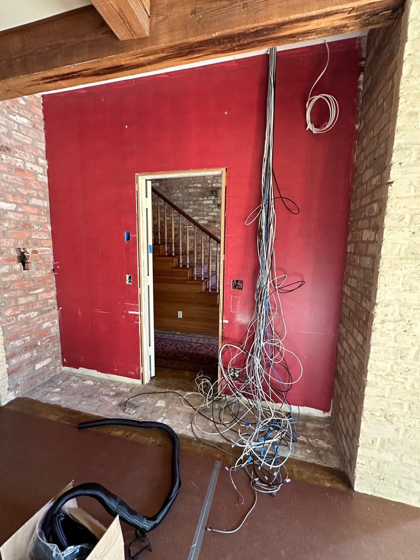 Tangled, exposed low-voltage wiring hanging down a wall before repair